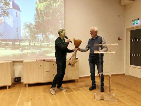 Sven Hertzman från Bollebygds församling överlämnar välförtjänta blommor till kvällens föreläsare, Christer Johansson,
