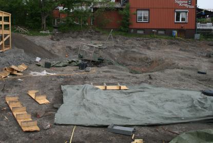 Utgrävningsplatsen delvis täckt av presenningar för att skydda mot sol och regn